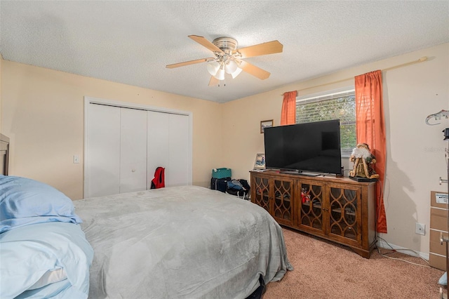 bedroom featuring ceiling fan, a closet, light colored carpet, and a textured ceiling