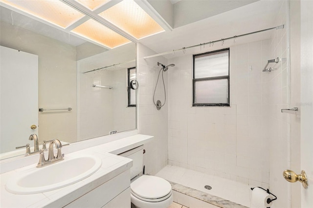 bathroom with vanity, toilet, and a tile shower