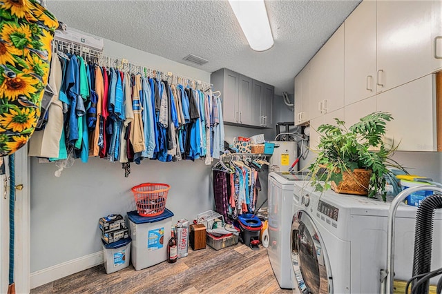 washroom featuring separate washer and dryer, cabinets, a textured ceiling, and wood-type flooring