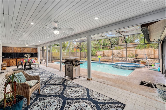 view of pool featuring glass enclosure, an in ground hot tub, ceiling fan, and a patio