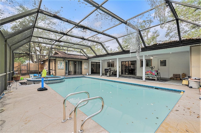 view of pool with glass enclosure, ceiling fan, and an in ground hot tub