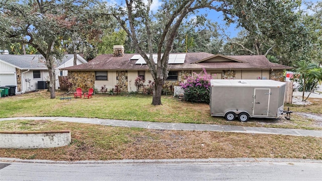 view of front of home with central AC unit, solar panels, and a front yard