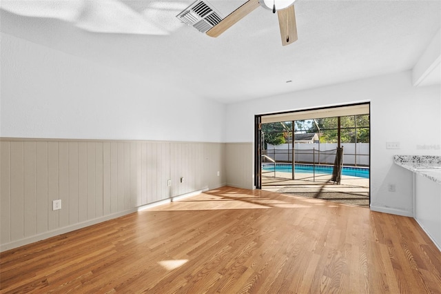 unfurnished room with ceiling fan, a textured ceiling, and light wood-type flooring