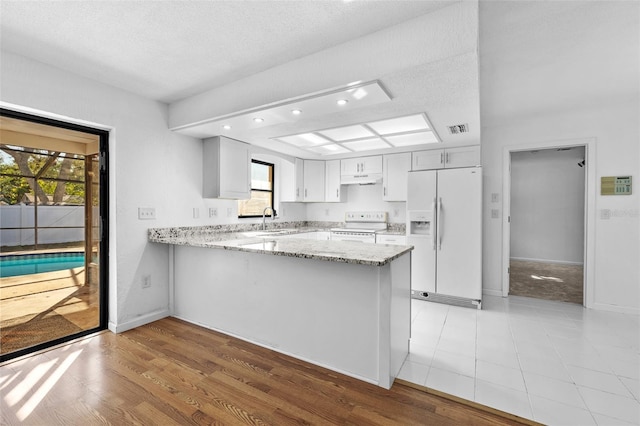 kitchen featuring kitchen peninsula, a textured ceiling, white appliances, sink, and white cabinets