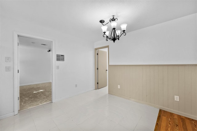 unfurnished room featuring an inviting chandelier and wooden walls