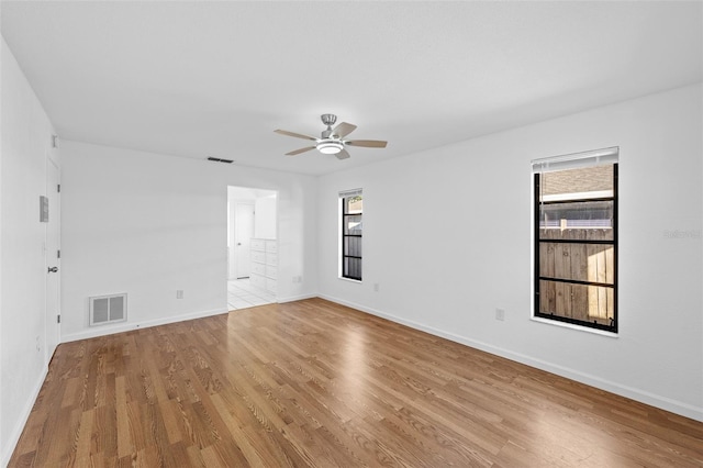 empty room with ceiling fan, a healthy amount of sunlight, and light wood-type flooring