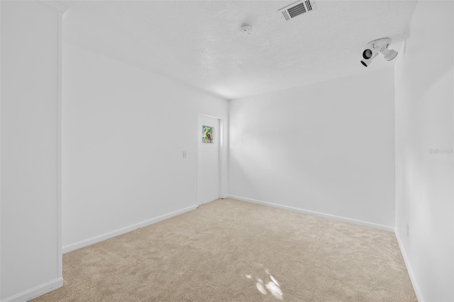 empty room featuring a textured ceiling and light carpet