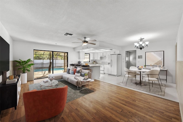 living room featuring ceiling fan with notable chandelier, a textured ceiling, and light wood-type flooring