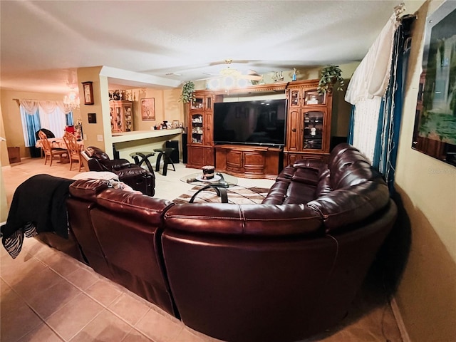 living room with tile patterned flooring and ceiling fan with notable chandelier