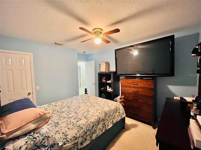 bedroom with ceiling fan, a textured ceiling, and light carpet