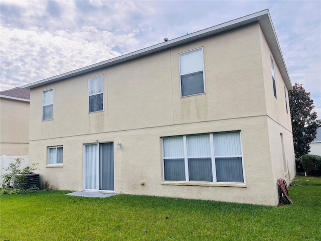 rear view of house featuring a lawn and central AC