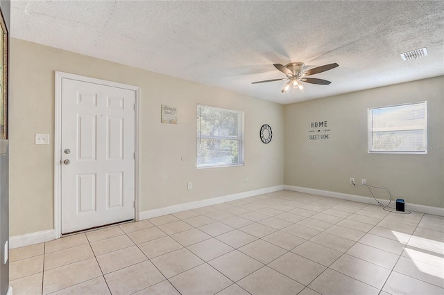 empty room with light tile patterned floors, a textured ceiling, and ceiling fan