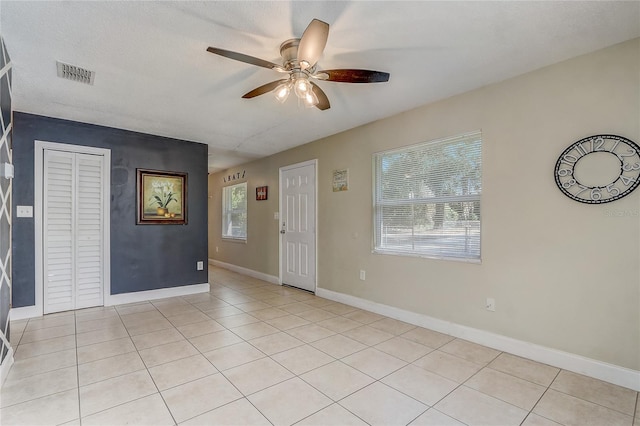 tiled spare room with a textured ceiling, plenty of natural light, and ceiling fan