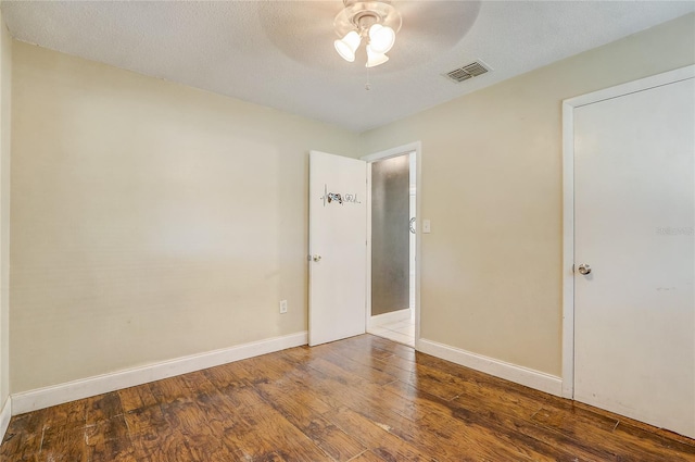 spare room with a textured ceiling, ceiling fan, and dark hardwood / wood-style floors