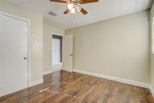 unfurnished bedroom with a closet, a textured ceiling, dark hardwood / wood-style floors, and ceiling fan