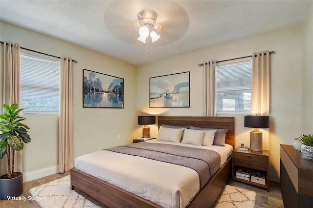 bedroom featuring ceiling fan, wood-type flooring, and multiple windows