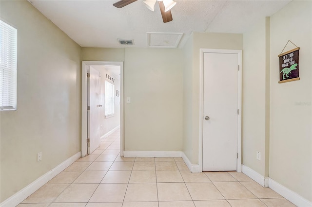 hallway featuring light tile patterned floors, a textured ceiling, and a wealth of natural light