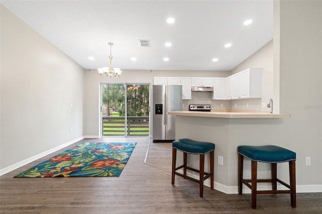 kitchen featuring kitchen peninsula, a kitchen breakfast bar, stainless steel appliances, dark wood-type flooring, and white cabinets