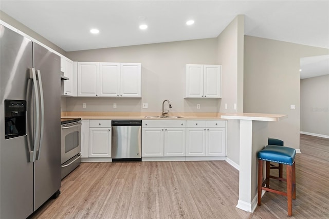 kitchen featuring white cabinets, appliances with stainless steel finishes, lofted ceiling, and sink