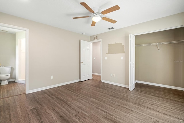 unfurnished bedroom featuring a closet, connected bathroom, dark hardwood / wood-style floors, and ceiling fan