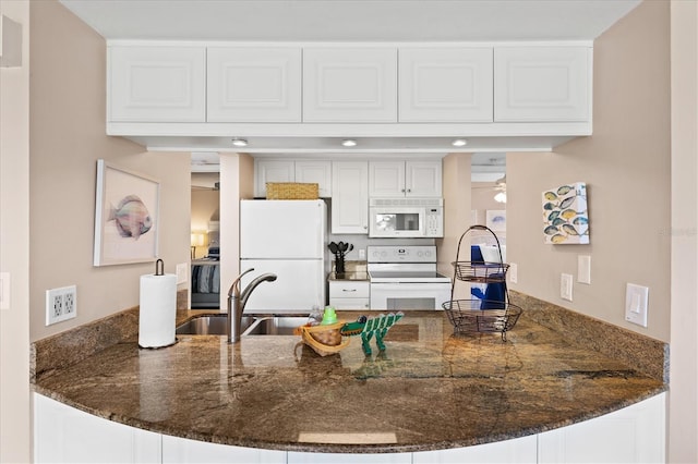 kitchen with white cabinets, white appliances, kitchen peninsula, and dark stone counters