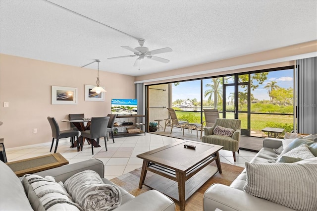 living room featuring ceiling fan, light tile patterned floors, and a textured ceiling