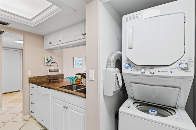 laundry area featuring light tile patterned floors, stacked washer / drying machine, and sink