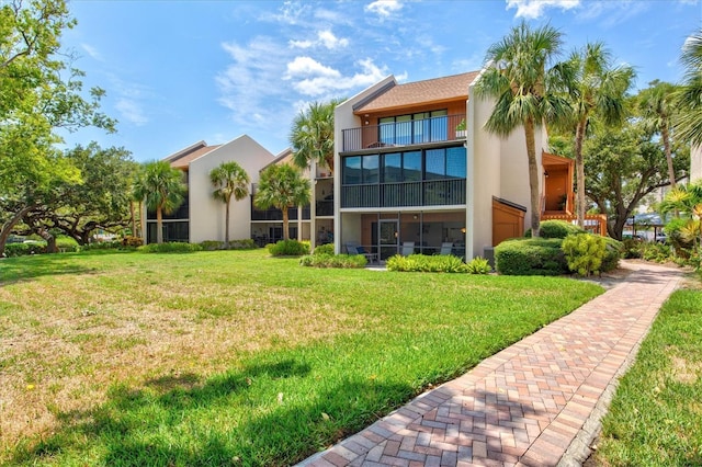 rear view of house with a lawn and a balcony