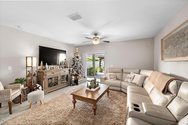 living room with ceiling fan, light tile patterned flooring, and a textured ceiling