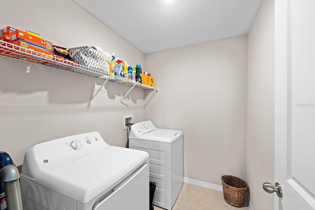 clothes washing area with light tile patterned floors, a textured ceiling, and washing machine and clothes dryer