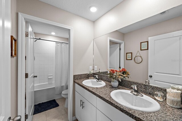 full bathroom with tile patterned flooring, a textured ceiling, toilet, shower / bath combo with shower curtain, and vanity