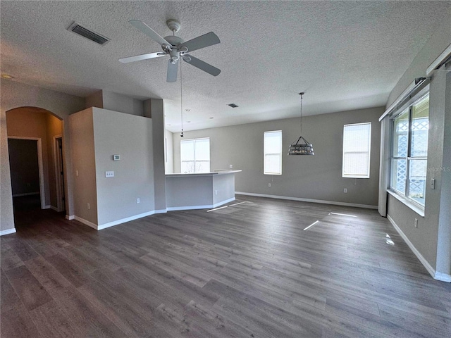 unfurnished living room featuring ceiling fan, dark hardwood / wood-style floors, and a textured ceiling