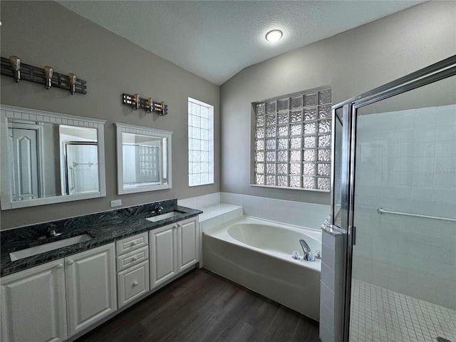 bathroom with vaulted ceiling, a textured ceiling, vanity, hardwood / wood-style flooring, and plus walk in shower