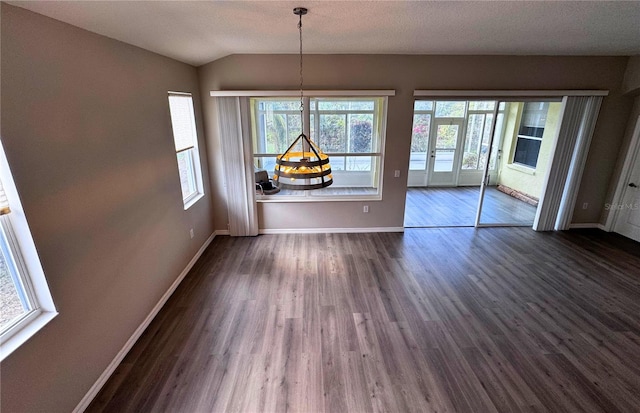 unfurnished dining area with dark wood-type flooring, lofted ceiling, and a textured ceiling