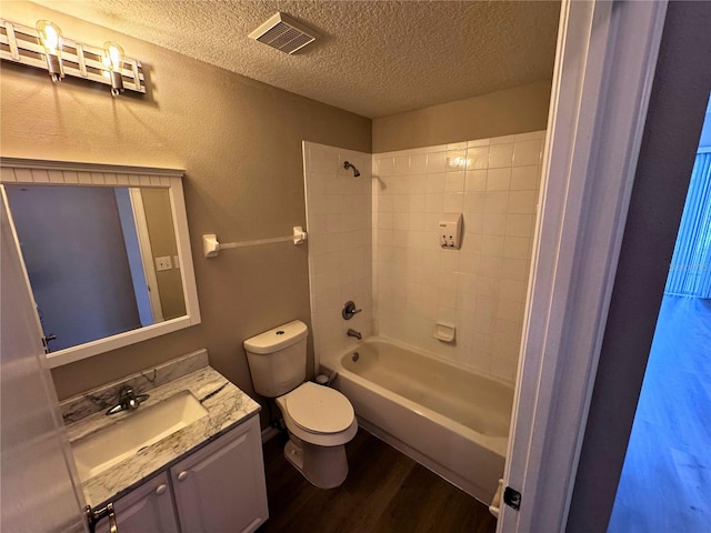 full bathroom with hardwood / wood-style floors, vanity, a textured ceiling, toilet, and tiled shower / bath