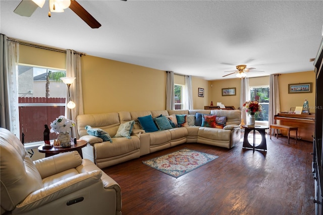 living room with dark wood-type flooring, ceiling fan, and a healthy amount of sunlight