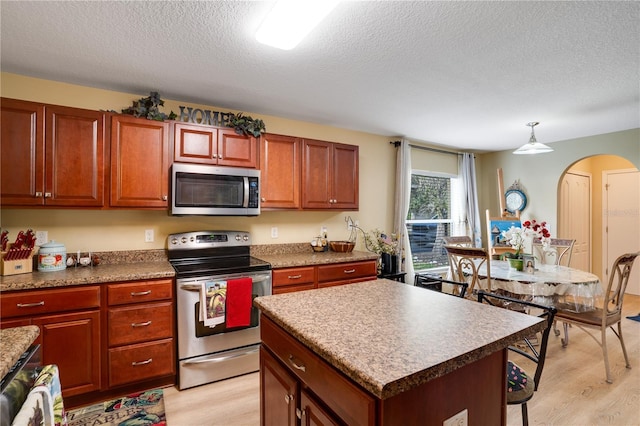 kitchen featuring a textured ceiling, a kitchen island, light hardwood / wood-style floors, and stainless steel appliances