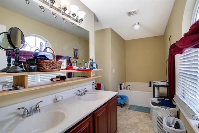 bathroom featuring tile patterned flooring, vanity, and a bath