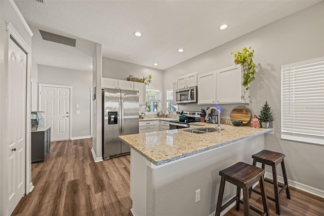 kitchen with white cabinets, kitchen peninsula, sink, and appliances with stainless steel finishes