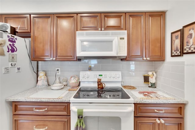 kitchen featuring light stone countertops, white appliances, and backsplash