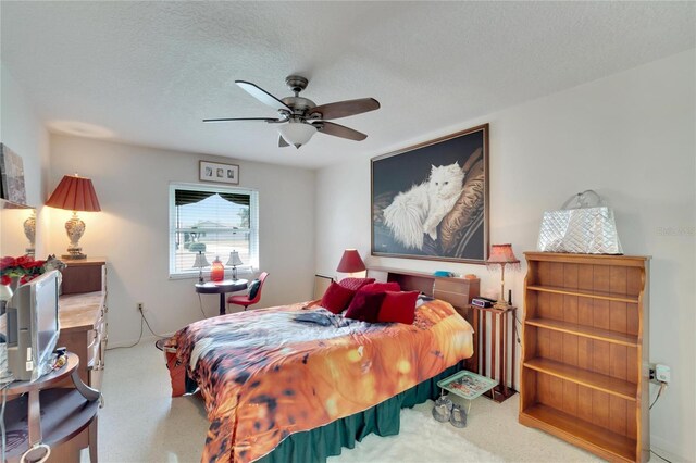 bedroom featuring ceiling fan, carpet floors, and a textured ceiling