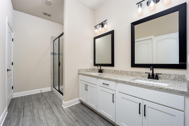 bathroom with hardwood / wood-style floors, vanity, and a shower with door