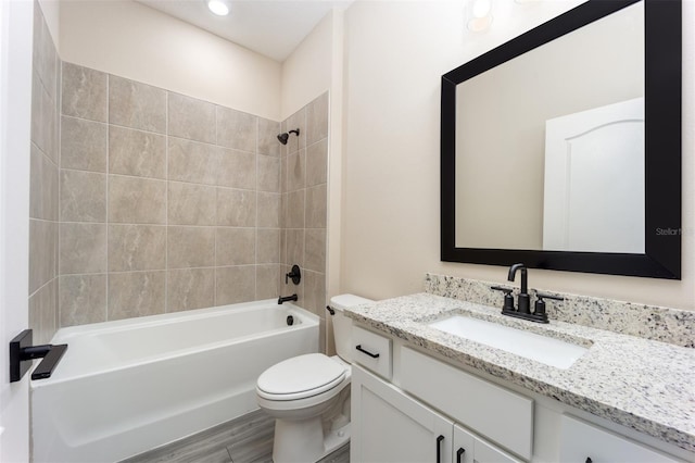 full bathroom featuring hardwood / wood-style flooring, vanity, toilet, and tiled shower / bath