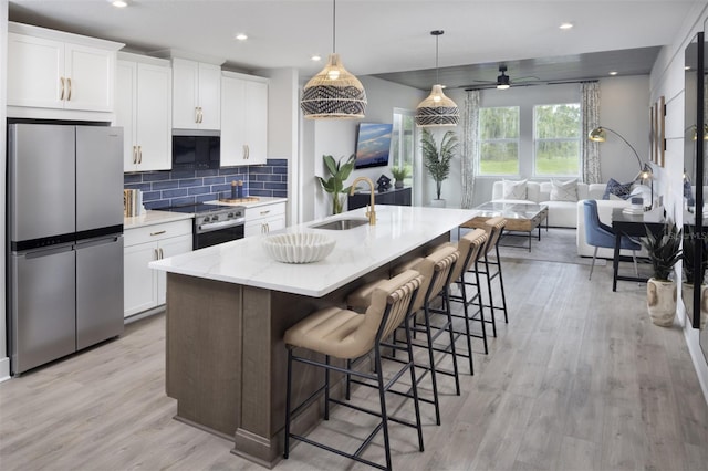 17390 Moonflower Dr Unit 102, Venice, FL 34293 - kitchen with a sink, white cabinetry, light wood-type flooring, stainless steel appliances, and decorative backsplash