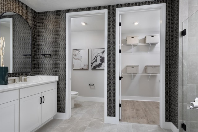 17390 Moonflower Dr Unit 102, Venice, FL 34293 - bathroom with baseboards, toilet, vanity, and a spacious closet