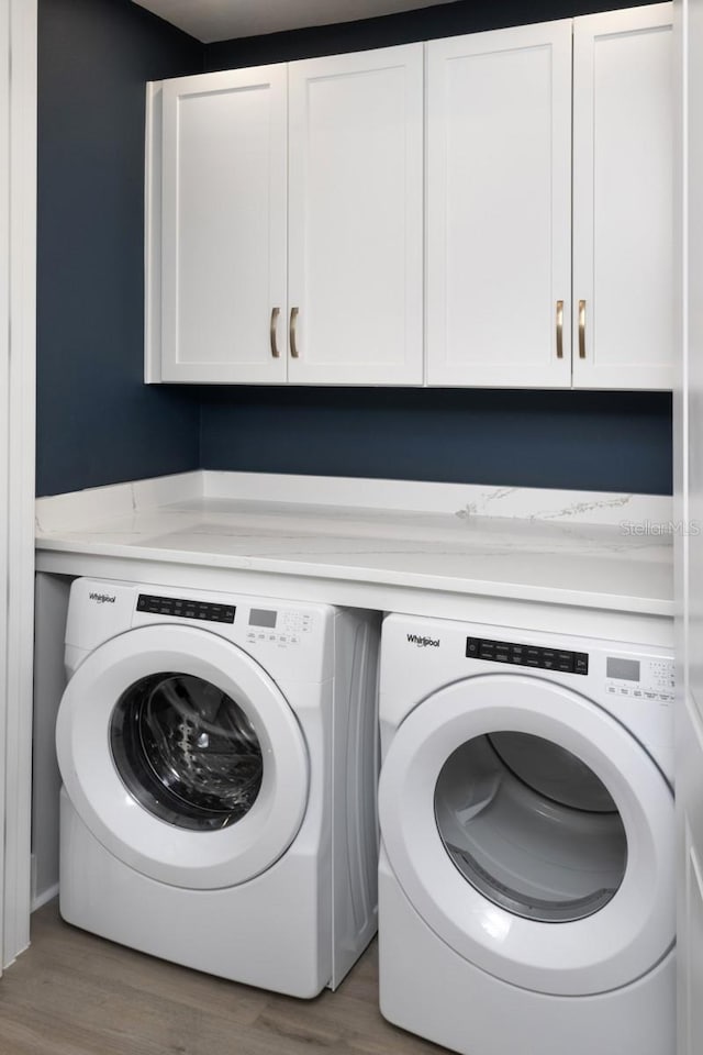 17390 Moonflower Dr Unit 102, Venice, FL 34293 - laundry area featuring wood finished floors, washing machine and clothes dryer, and cabinet space