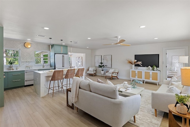 living room featuring ceiling fan, light wood-type flooring, and sink