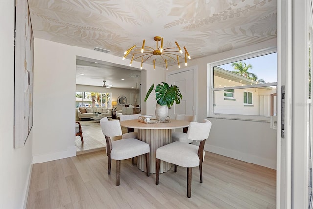 dining area with light hardwood / wood-style floors and ceiling fan with notable chandelier