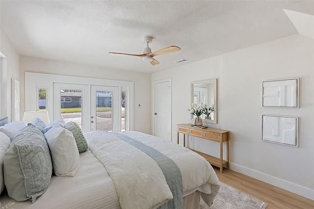 bedroom with access to outside, french doors, ceiling fan, light wood-type flooring, and a textured ceiling