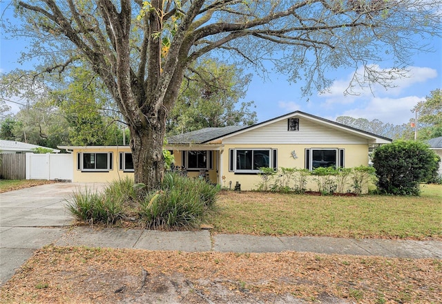 view of front of property with concrete driveway, fence, a front yard, and stucco siding